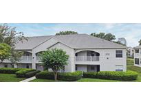 Exterior view of the property featuring white facade, grey roof, well-manicured lawn and mature trees at 570 Cranes Way # 248, Altamonte Springs, FL 32701