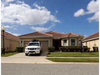 Charming single-story home with a tile roof, manicured lawn, and a well-maintained garden, complemented by a lovely sky at 3047 Sangria St, Kissimmee, FL 34744