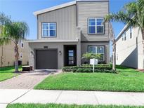 Charming two-story home featuring modern architecture, a well-manicured lawn, and a paved driveway at 8938 Cabot Cliffs Dr, Davenport, FL 33896