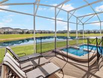 Screened-in pool and spa with a view of a scenic pond and neighboring homes at 8938 Cabot Cliffs Dr, Davenport, FL 33896