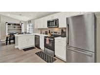 Modern kitchen featuring stainless steel appliances, white cabinetry, and wood flooring at 188 Ridgemont Ct, Davenport, FL 33896