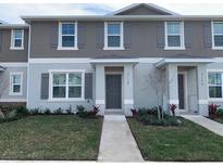 Two-story townhome with gray siding, landscaping, and walkway at 6138 Galloping Dr, Apopka, FL 32712