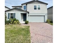 Two-story house with gray siding, gray shutters, and a brick driveway at 291 Whistling Duck Trl, St Cloud, FL 34771