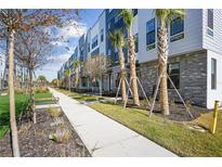 Modern townhomes with brick accents, palm trees, and landscaped walkway create inviting curb appeal at 2110 Whitney Marsh Aly, Orlando, FL 32804