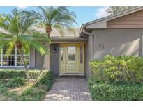 Inviting front entrance with beautiful glass front door and lush tropical landscaping with palm trees and a brick walkway at 51 Oakleigh Ln, Maitland, FL 32751