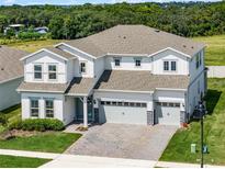 Spacious two-story home featuring a three-car garage, manicured lawn, and a dense forest in the background at 3198 Sailing Pier Ave, Winter Garden, FL 34787