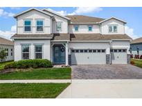 Charming two-story home with a three-car garage, neat landscaping and a manicured front lawn on a sunny day at 3198 Sailing Pier Ave, Winter Garden, FL 34787