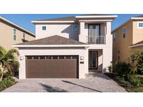 Two-story home featuring a brown garage door, balcony, neutral paint, and brick paved driveway at 7554 Marker Ave, Kissimmee, FL 34747