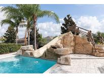 A stunning private pool features a rock slide and lush landscaping, perfect for relaxing and entertaining at 7554 Marker Ave, Kissimmee, FL 34747