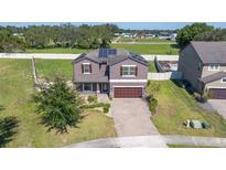 Beautiful two-story home with solar panels, a brick driveway, and a manicured front lawn at 556 Keyhold Loop, Apopka, FL 32712