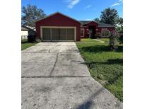 Charming red single-story home featuring a two-car garage and a well-manicured lawn at 305 Erie Ct, Kissimmee, FL 34759