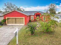 Charming single-Gathering home with a red exterior, lush landscaping, and a well-maintained front yard at 305 Erie Ct, Kissimmee, FL 34759