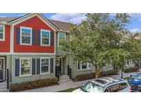 Charming townhome featuring a colorful exterior with black shutters, inviting curb appeal, and manicured landscaping at 1349 Mill Stream Ln, Winter Springs, FL 32708