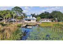 Beautiful waterfront home featuring a dock, a blue roof, and a charming outdoor patio, perfect for lakeside living at 1322 Susannah Blvd, Orlando, FL 32803