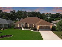 Charming single-story home featuring a well-manicured lawn and a screened two-car garage at sunset at 5825 Princess Caroline Pl, Leesburg, FL 34748