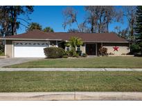 Tan house with red roof, white garage door, and landscaped lawn at 4423 Real Ct, Orlando, FL 32808