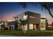 Stunning modern home with a sleek dark and white exterior, complemented by a well-manicured lawn at twilight at 2522 Lafayette Ave, Winter Park, FL 32789