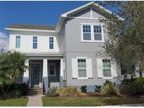 Charming two-story home featuring a blend of white and gray tones, complemented by a lush, landscaped front yard at 7997 Greengard St, Orlando, FL 32827