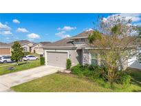 Single-story home with gray siding, attached garage, and landscaped yard at 1162 Alder Tree Dr, Apopka, FL 32703