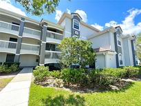View of the condo building with gray paint, white railings, and well-maintained landscaping at 13803 Fairway Island Dr # 1627, Orlando, FL 32837