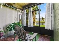 Serene screened porch featuring wood flooring, a comfortable chair, and views of the lush greenery and pond at 5783 Peregrine Ave # C07, Orlando, FL 32819