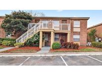 Inviting brick two-story condo building featuring landscaped grounds, a parking lot and stairwell access to upper level units at 476 Banyon Tree Cir # 104, Maitland, FL 32751