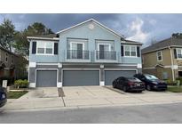 Two-story townhome featuring a light blue facade, three garage doors, and two small balconies at 3010 San Jacinto Cir # 3010, Sanford, FL 32771