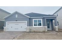 New home exterior with gray siding, white garage door, and stone accents at 1173 Basalt Ln, Sanford, FL 32771