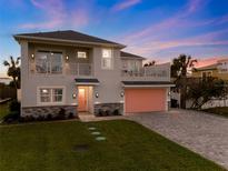 Two-story house with a pink garage door, stone accents, and a landscaped lawn at 4260 S Atlantic Ave, Port Orange, FL 32127