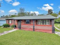 Charming single-story brick home with a fenced-in front porch and well-maintained lawn, presenting curb appeal at 1904 Historic Goldsboro Blvd, Sanford, FL 32771