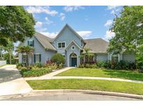 Charming home with a beautifully landscaped front yard, lush gardens, and a welcoming blue facade at 2523 Madron Ct, Orlando, FL 32806