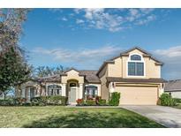 Charming two-story home featuring a manicured lawn, colorful landscaping, and an attached two-car garage at 36711 Alaqua Ct, Eustis, FL 32736