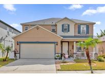 Two-story house with tan exterior, blue accents, and a landscaped yard at 2879 Paynes Prairie Cir, Kissimmee, FL 34743