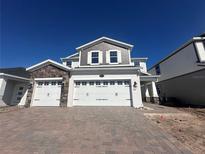 Beautiful two-story home featuring a three-car garage, stone accents, and a brick driveway at 5274 Teirgarten St, Saint Cloud, FL 34771