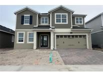 Two story home featuring a two car garage, neutral paint scheme, and a brick driveway at 5304 Teirgarten St, Saint Cloud, FL 34771