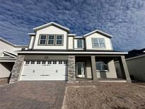 Two-story house with white siding, stone accents, and a three-car garage at 5280 Teirgarten St, Saint Cloud, FL 34771