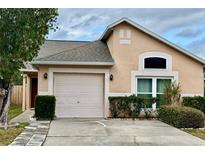 Tan one-story house with a two-car garage and landscaped yard at 12845 Parkbury Dr, Orlando, FL 32828