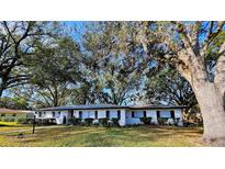 Ranch style home with white brick exterior, landscaping, and mature trees at 5528 Flamingo Ave, Lakeland, FL 33809