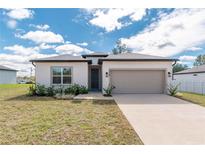 Inviting single-story home featuring a neutral color scheme, attached two-car garage, and well-maintained landscaping at 8908 Sw 133Rd Ln, Ocala, FL 34473