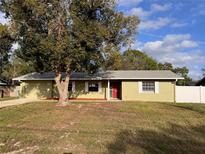 Charming single-story home featuring a red door, white trim, and large shade tree at 1337 Gaynor Ct, Deltona, FL 32725