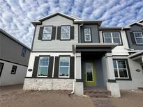 Two-story house with gray and white siding, dark shutters, and a lime green front door at 1360 Lumpini St, St Cloud, FL 34771