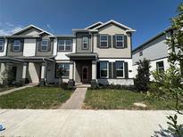 Charming two-story townhome with gray and white facade, dark shutters, and a red front door at 1364 Lumpini St, St Cloud, FL 34771
