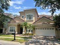 Charming two-story home boasts a two-car garage, a beautiful red tile roof, and lush landscaping with palm trees at 7014 Phillips Cove Ct # 27, Orlando, FL 32819