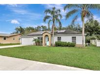 Charming single-story home with a well-manicured lawn, solar panels, and a welcoming light-blue front door at 1053 E Hancock Dr, Deltona, FL 32725