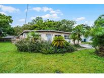 Charming single-story home with lush landscaping, palm trees and vibrant flower beds in a verdant front yard at 4908 Seminole Ave, Winter Park, FL 32792