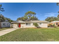 Charming single-story home with a well-manicured lawn, a red front door, and a lovely palm tree in the front yard at 1009 Perkins St, Leesburg, FL 34748