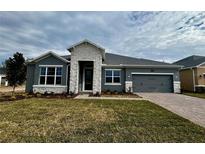 Single-story home with gray siding, stone accents, and a two-car garage at 371 Lady Palm St, Apopka, FL 32703