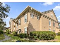 Well-maintained condo with neutral tones, brown shutters, manicured bushes, and green grass at 14304 Fredricksburg Dr # 420, Orlando, FL 32837