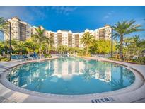 A relaxing, tropical pool with lounge chairs, palm trees and an attractive building reflecting in the water at 14501 Grove Resort Ave # 1332, Winter Garden, FL 34787