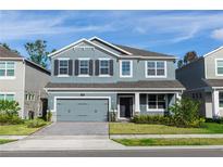 Charming two-story home with a brick driveway, gray exterior, shutters, and a well-maintained front yard at 5648 Green Arrow Pl, Sanford, FL 32773